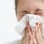 Woman sneezing in a tissue