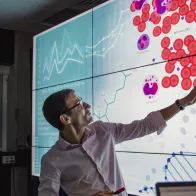 Crowd looking at big screen with data