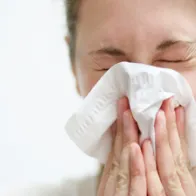 Woman sneezing in a tissue