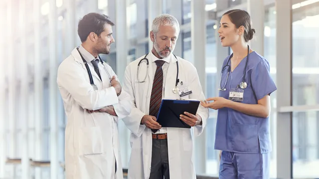 Three doctors standing discussing in hallway