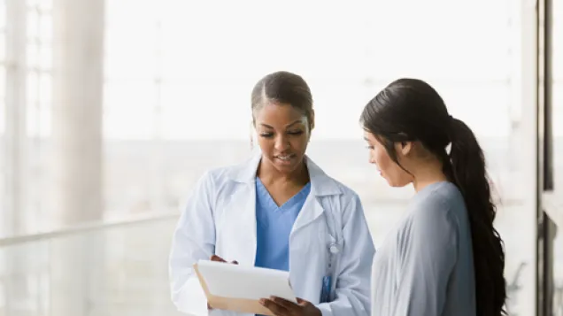 Female doctor and female patient standing looking at document