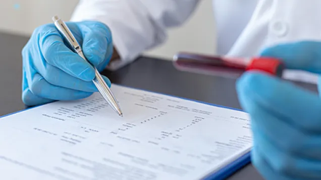 Image of hands with gloves holding blood test and checking a list