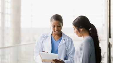 Female doctor and female patient standing looking at document